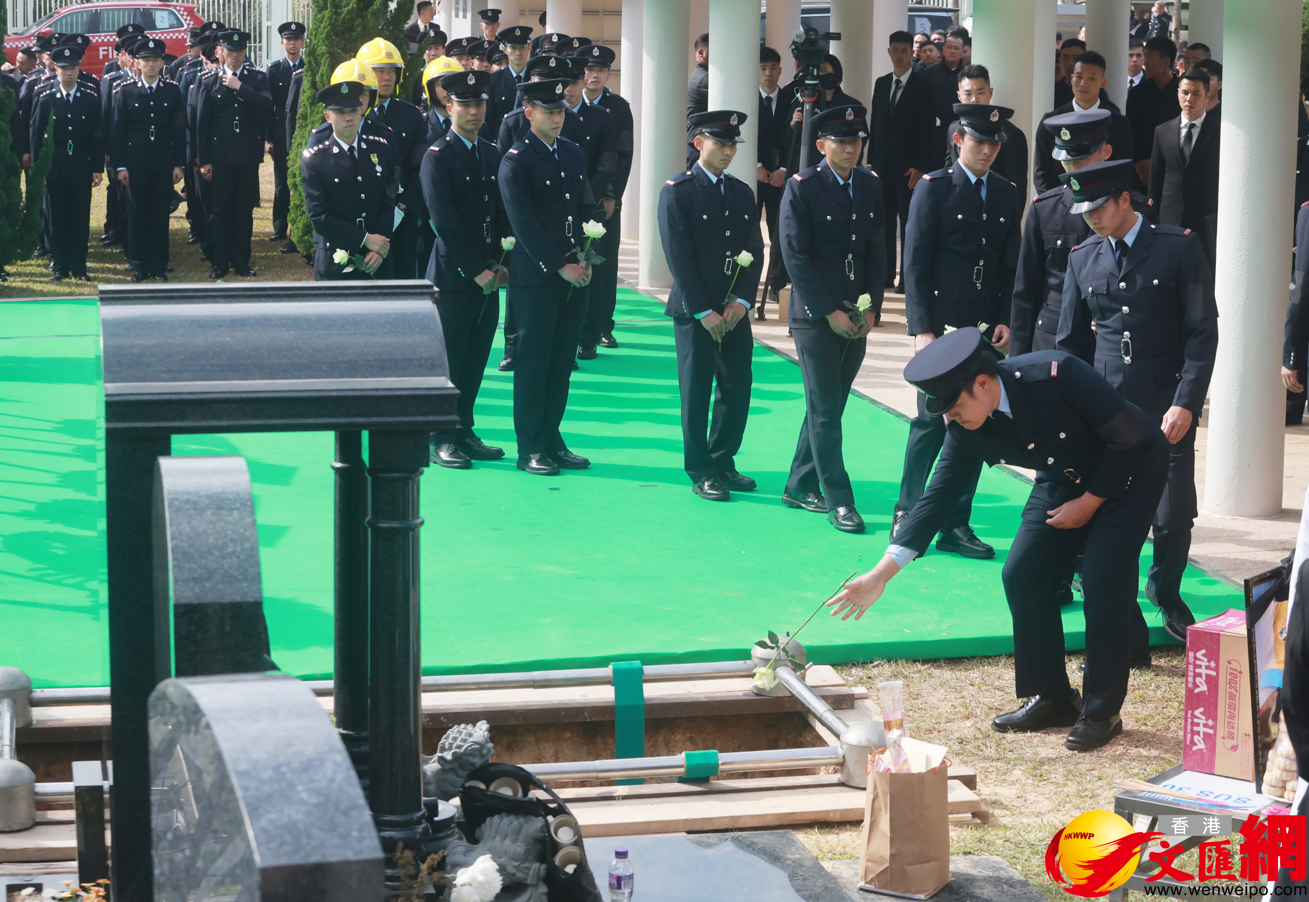 當靈柩被送下墓穴，親友及(ji)同袍最後輪流上前(qian)獻花(huā)，鞠躬緻意。（香港文(wén)匯報記者郭木(mù)又(yòu)攝）