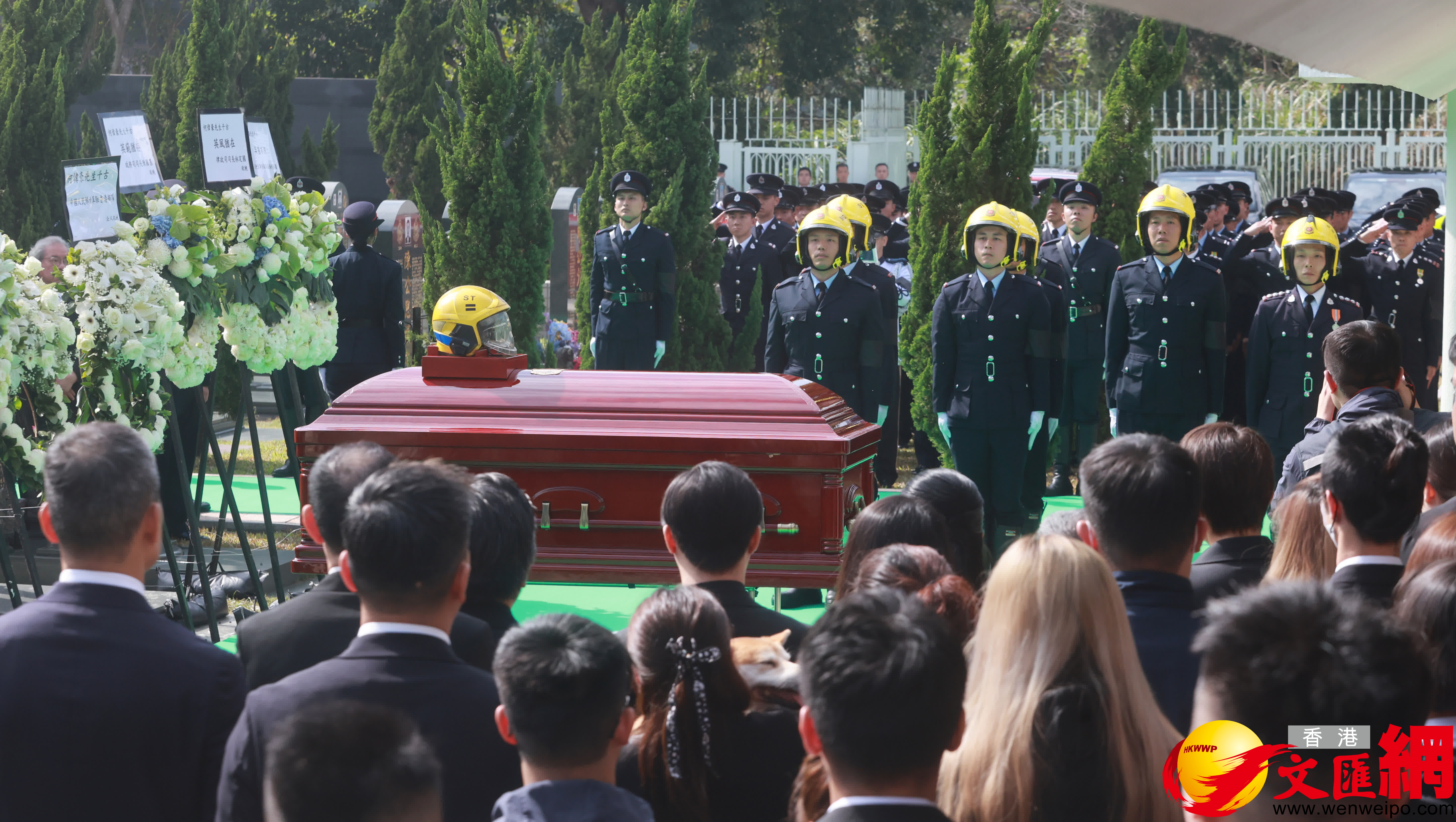 消防人(ren)員將何偉豪生(sheng)前(qian)使用(yong)的(de)消防頭盔擺放靈柩後，靈柩由工(gong)作(zuò)人(ren)員移至墓穴下葬。（香港文(wén)匯報記者郭木(mù)又(yòu)攝）